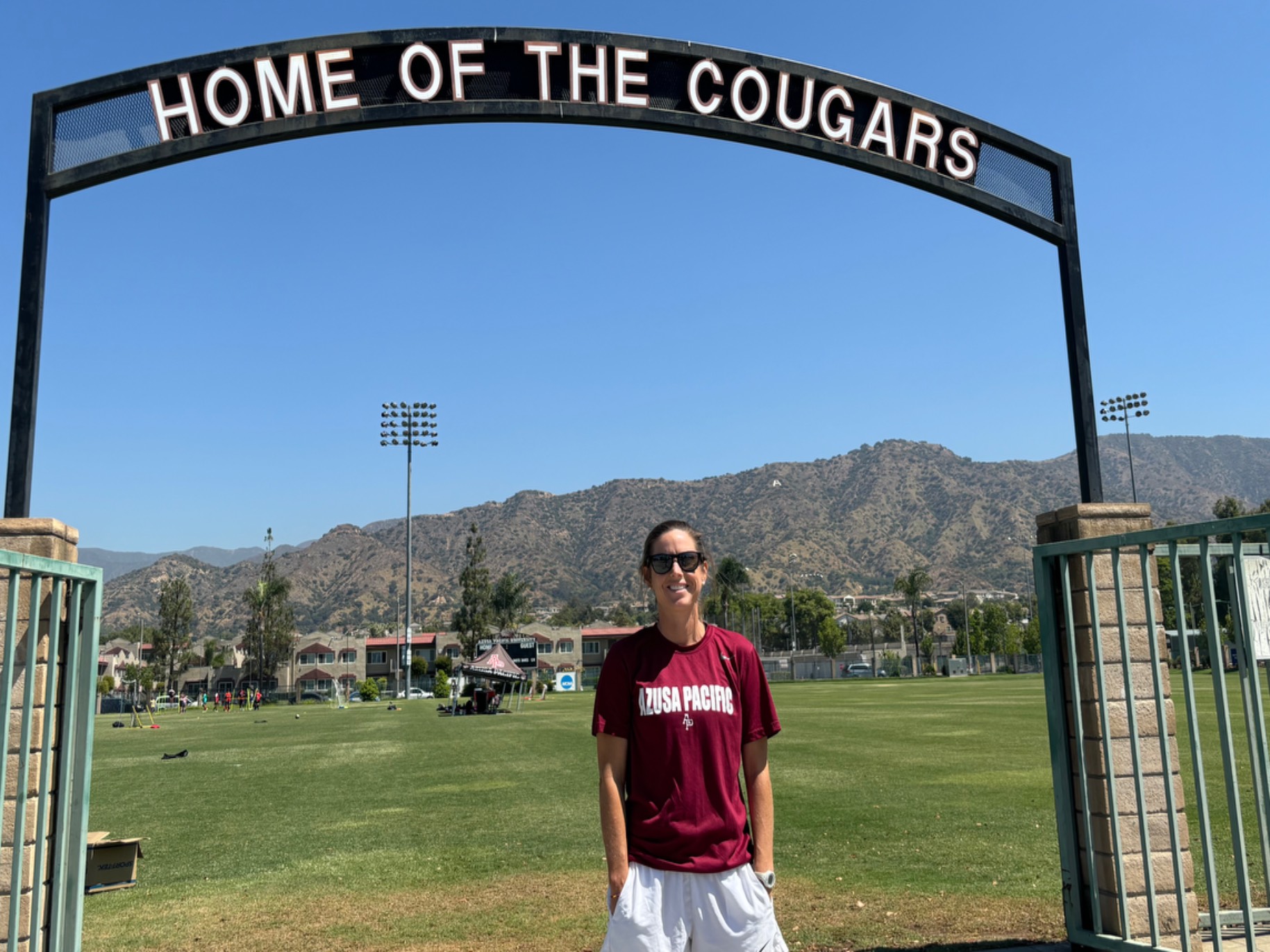 Brooke Lincoln stands outside the soccer field, beautiful mountains in the background on a clear, sunny day