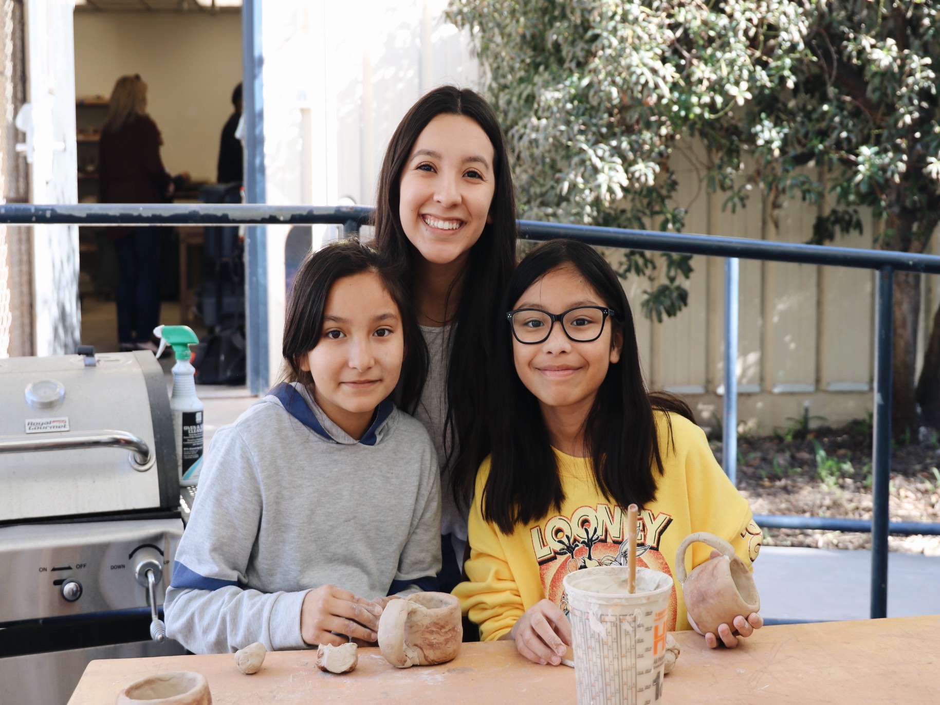 An APU student and two children smile for the camera.