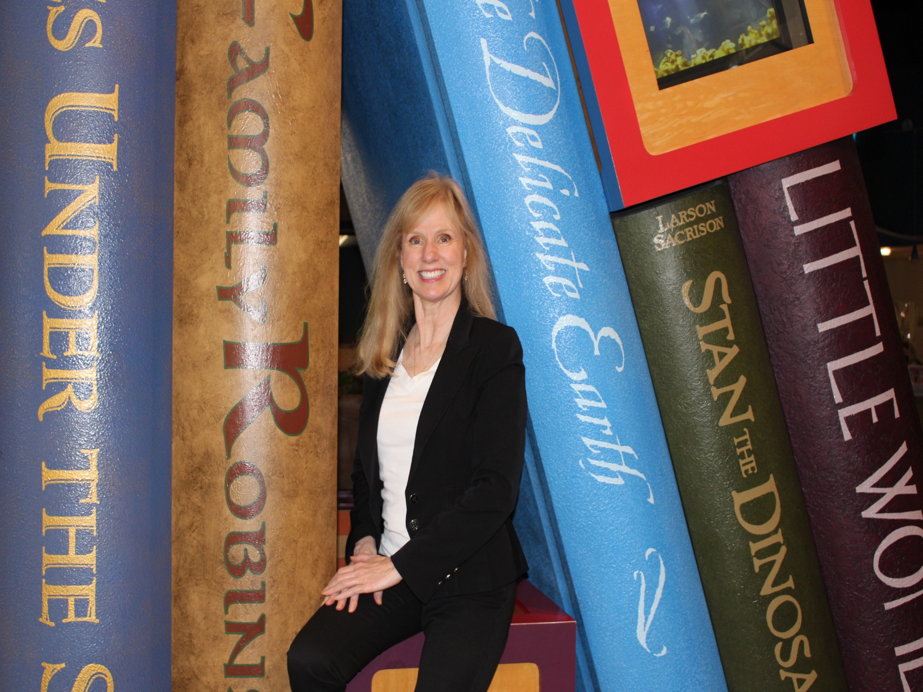 Cynthia dollins smiles in front of large books on display