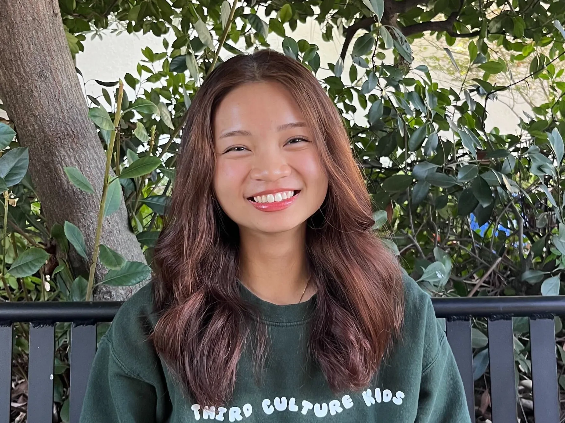 Grace Nguyen smiles on a bench on campus.