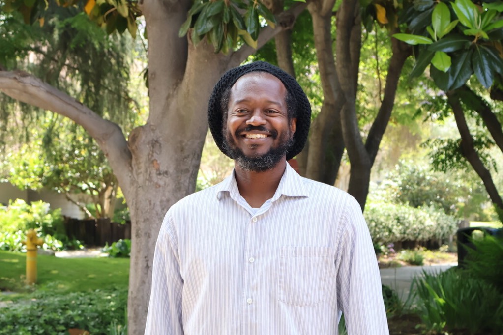 Larry smiles outside the library near trees