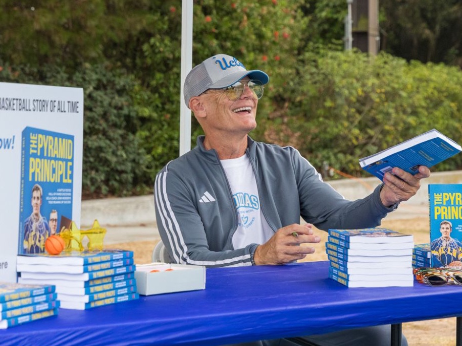 Paul Weissenstein hands a book to a reader at an outdoor book signing.