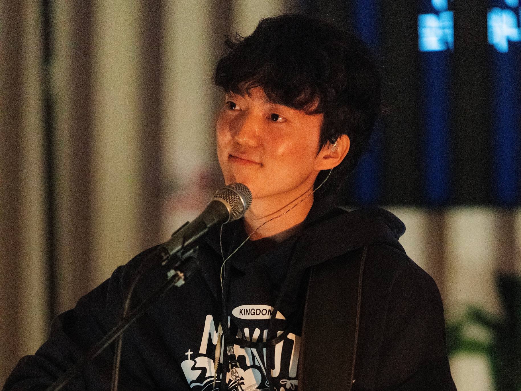 Heejae Jeong looking into the crowd as he plays guitar