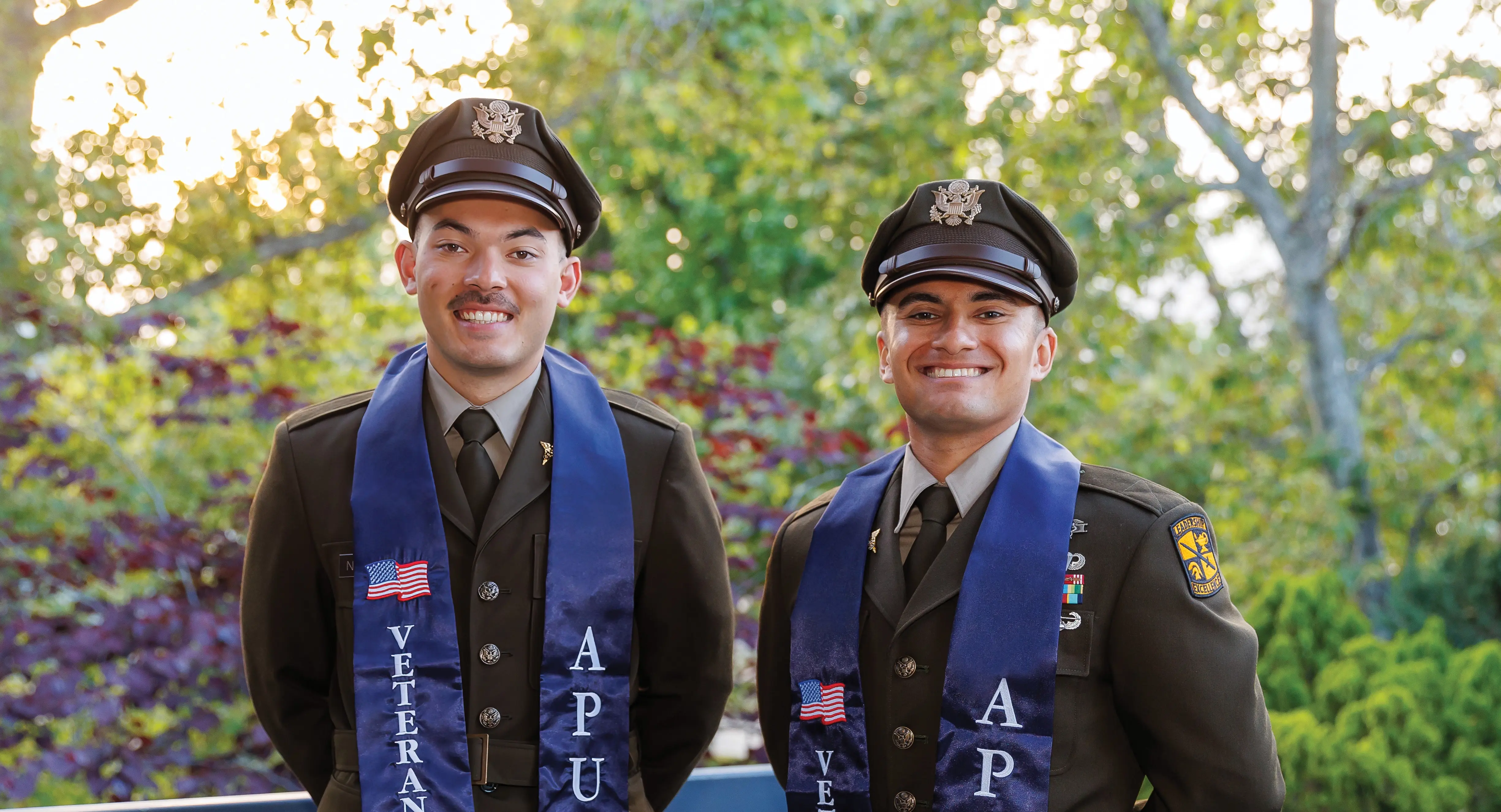 Cover of APU Life showing two graduates who are also military members.