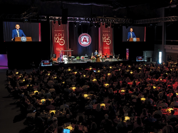 Adam Morris on a stage speaking to a group of people.