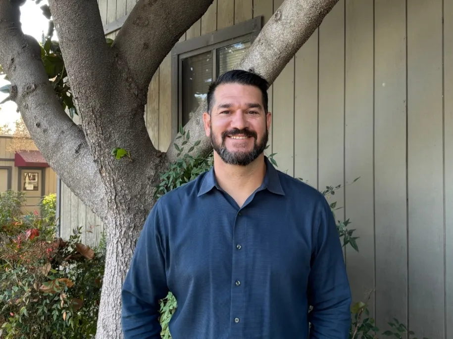 coba smiles outside his office on east campus on a sunny day