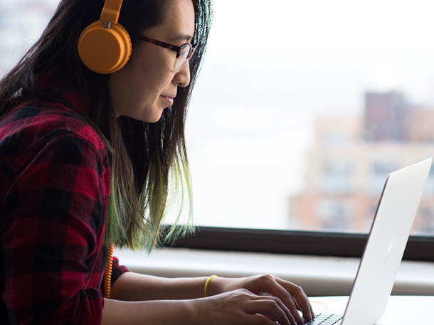 student wearing headset and using laptop