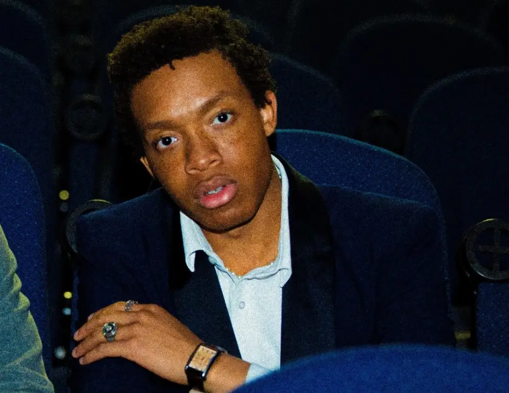 Student seated in a theater looking at camera 