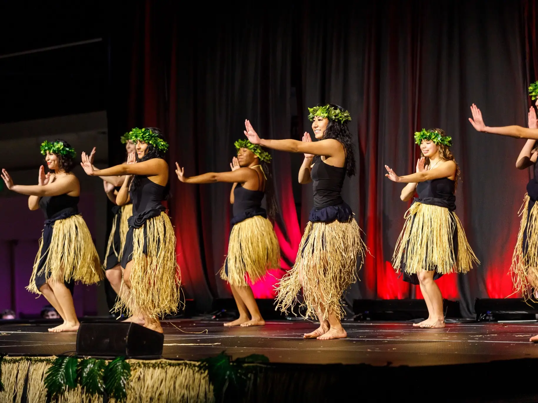 female students hula dance on stage at APU’s annual luau