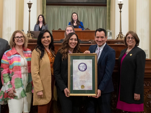 Jenica Morin-Pascual smiling as she holds the 48th District Woman of the Year Award