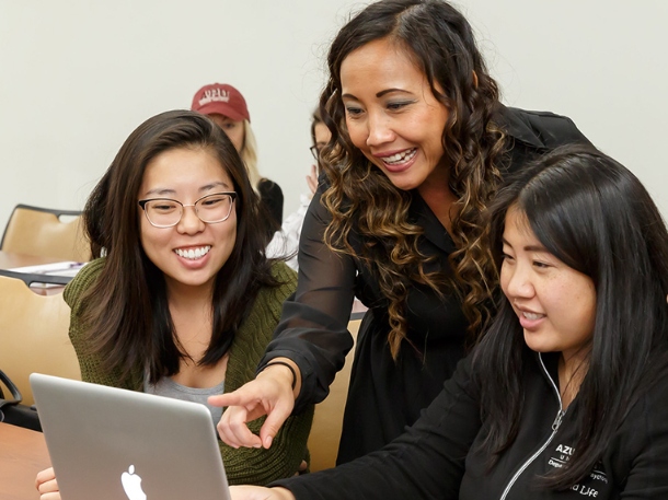 students using a laptop during class and interacting with professor