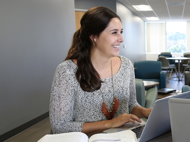 students smiling and talking while using her laptop