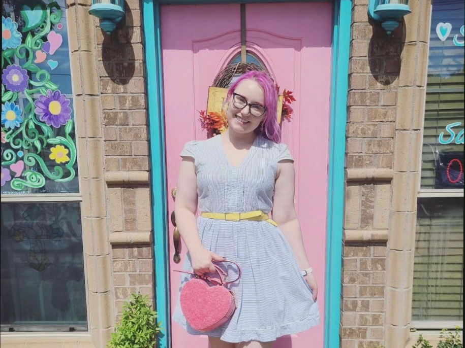 Kelsey smiles in a flowy dress outside a storybook-like house