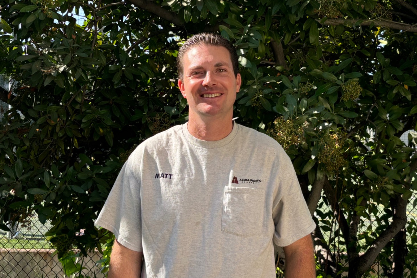  matt smiles outside his office, surrounded by green trees