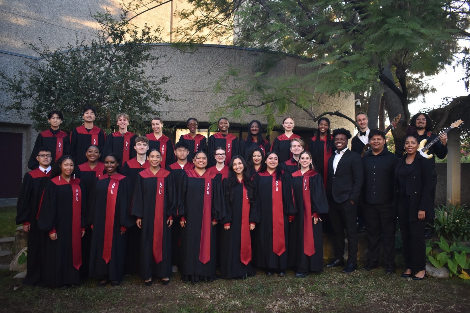 Image of the gospel choir performing in a stage wearing black gown with details in red.