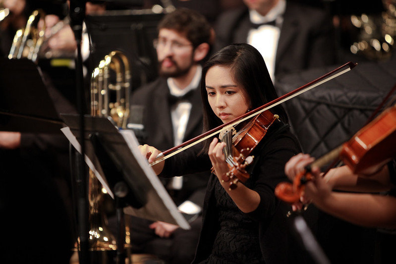 student wearing black and playing the violin during orchestra