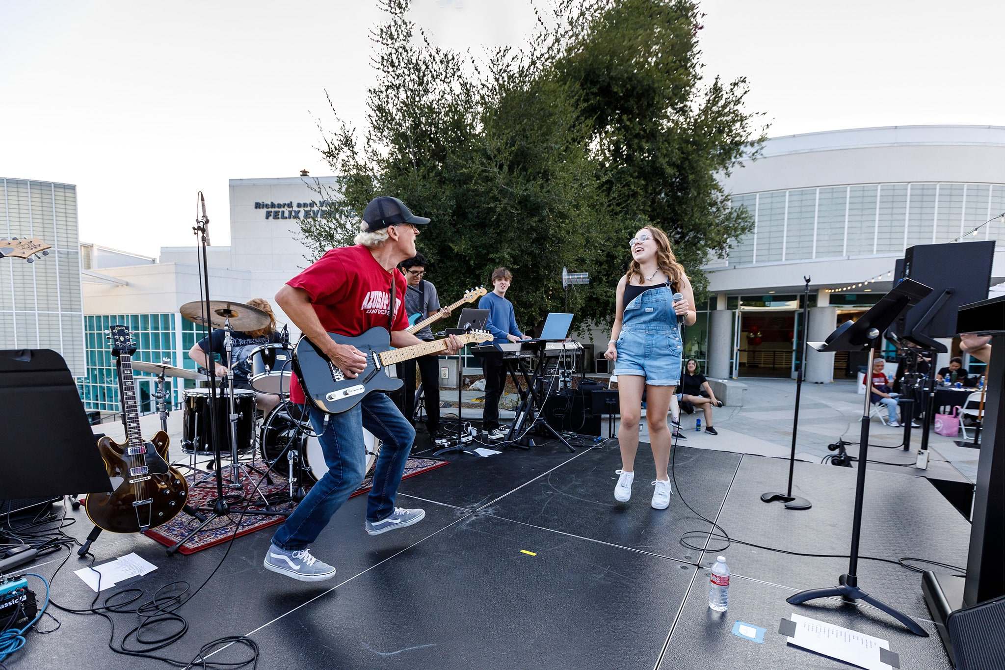 a student singing and a faculty playing the guitar on the stage during event on campus