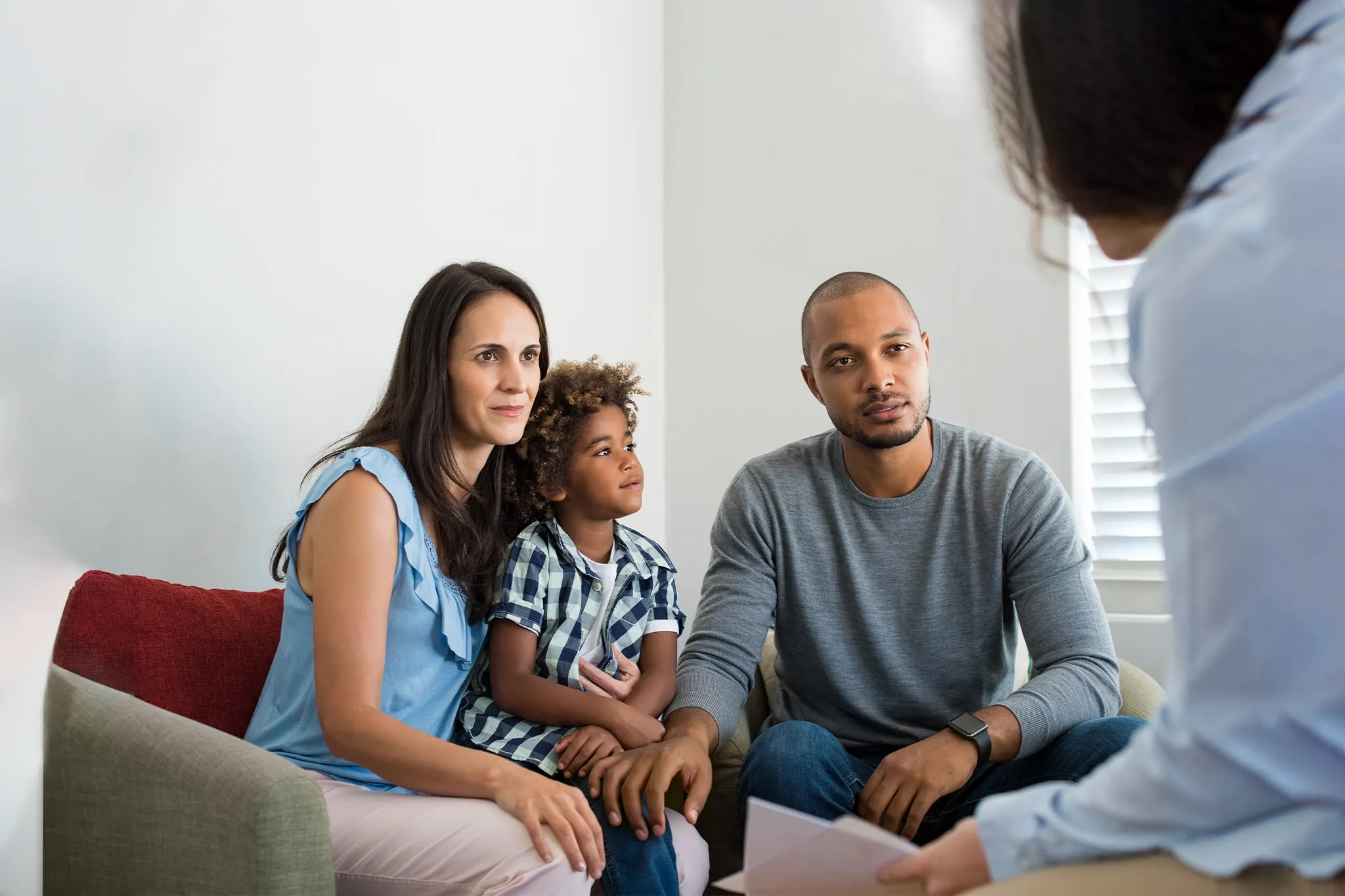 A man, woman, and child sitting on a couch speaking with counselor