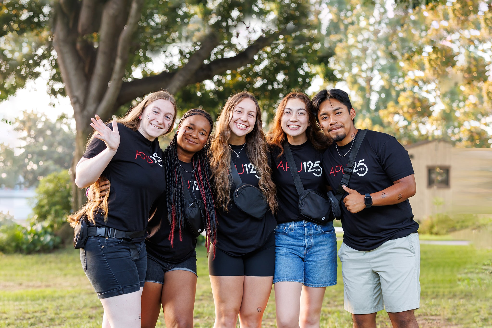 APU students smiling wearing 125th anniversary shirt