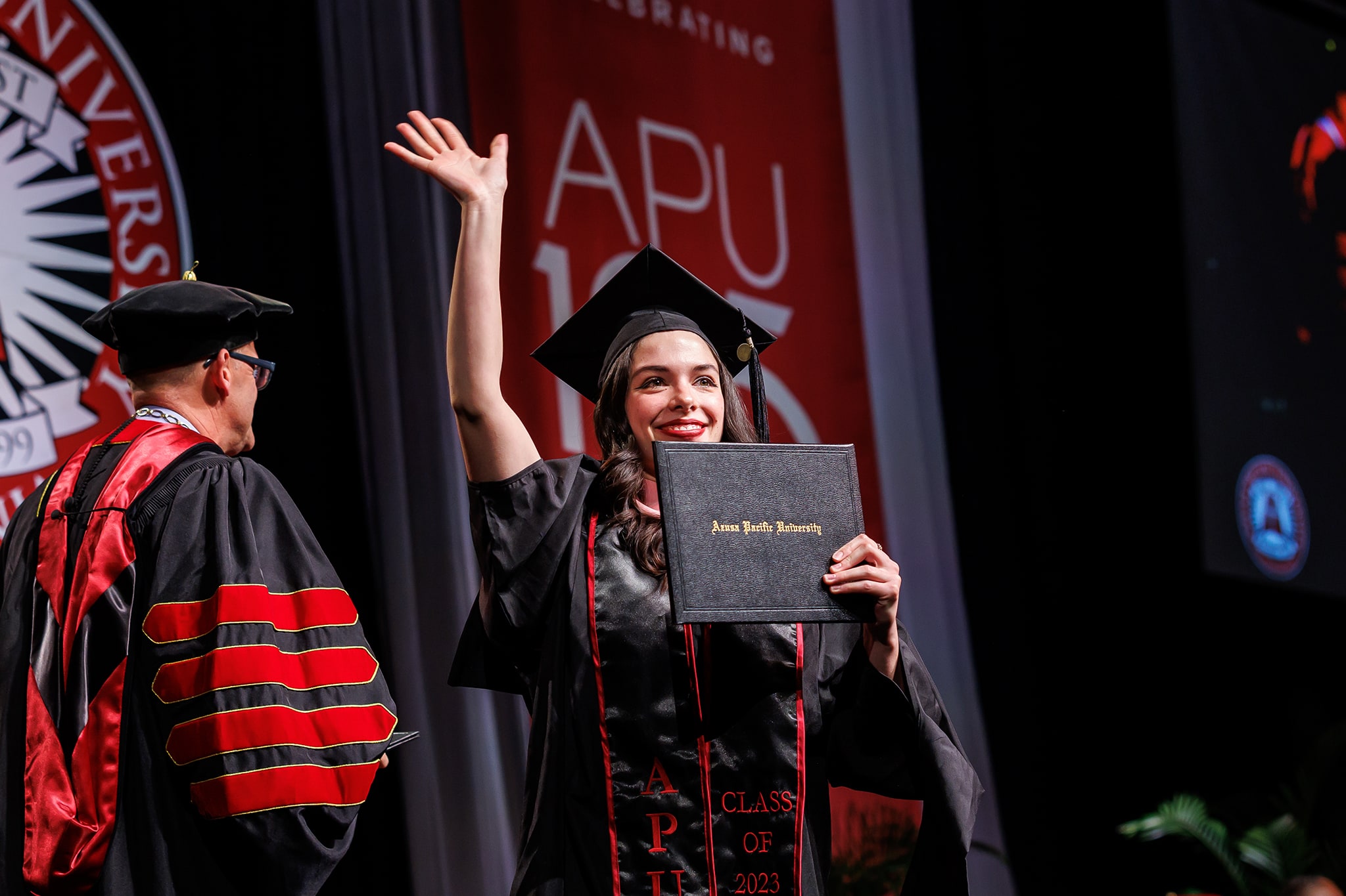 student holding diploma during commencement ceremony