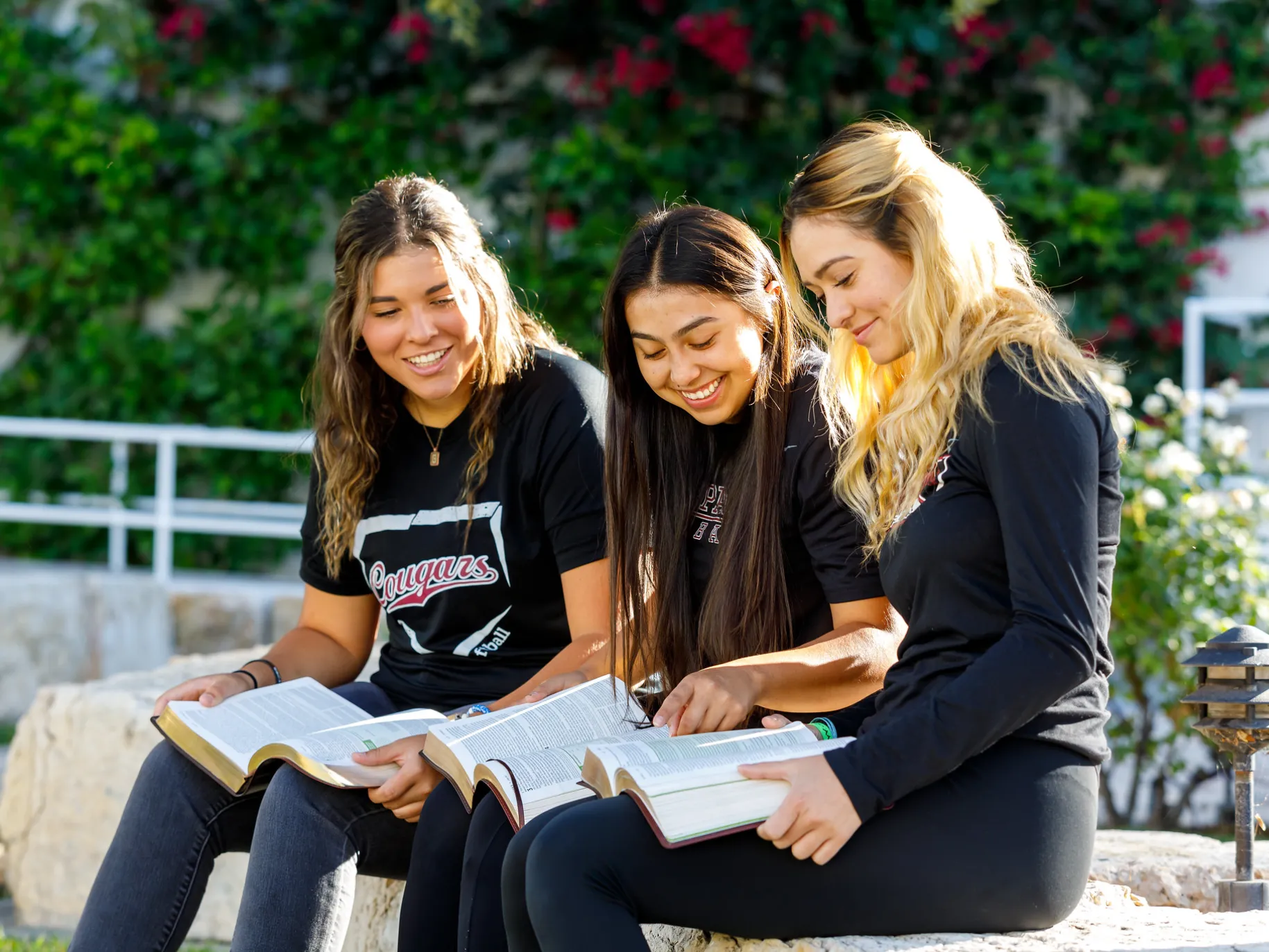 Three female students read their Bibles together.