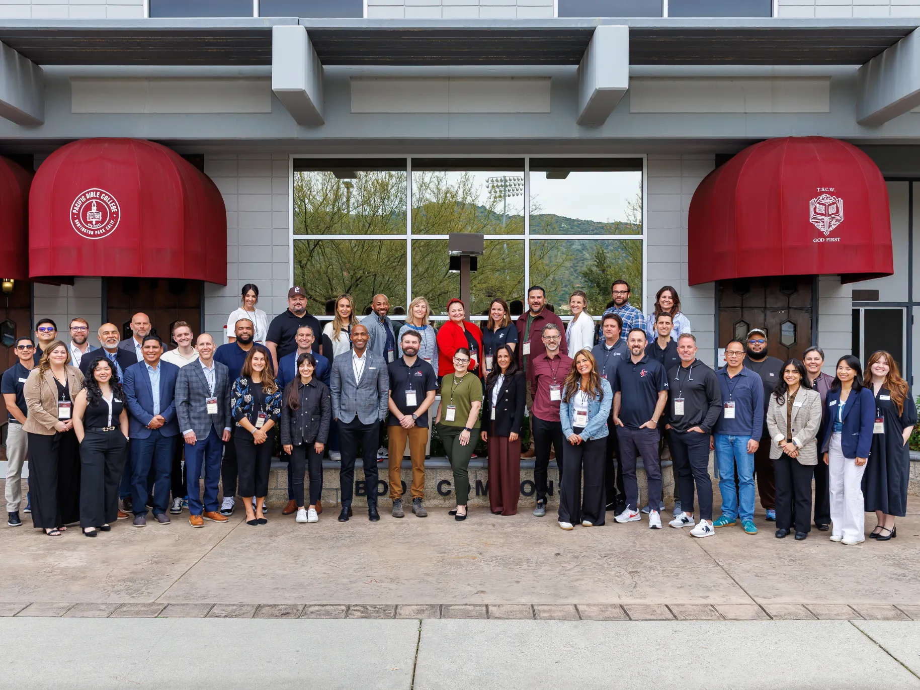 A group of workers from churches, nonprofits, and Christian schools stands in front of a building on APU's campus.