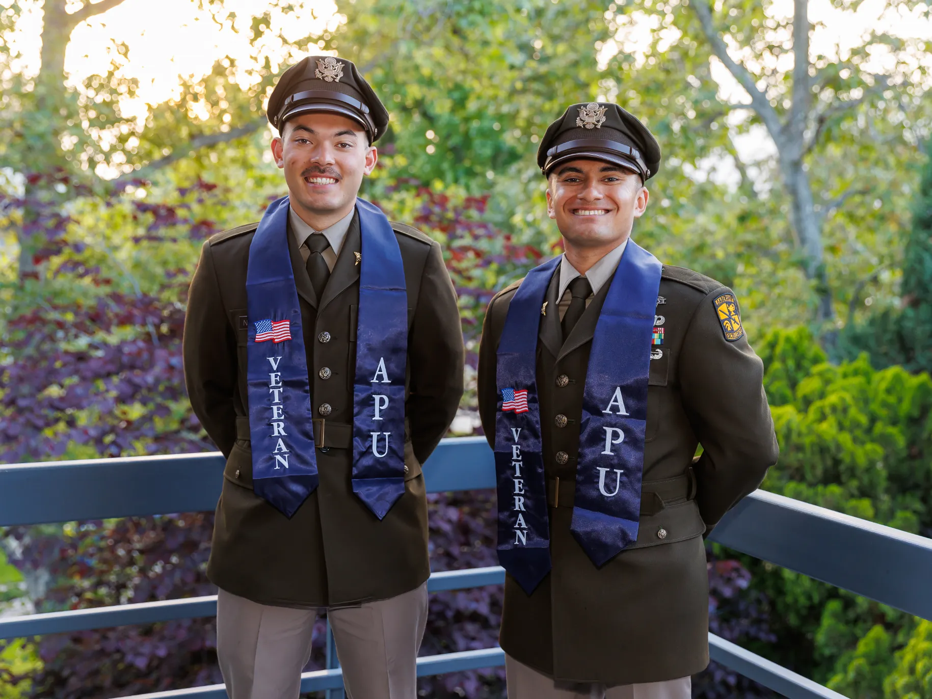 Two APU veteran students smile before their graduation ceremony