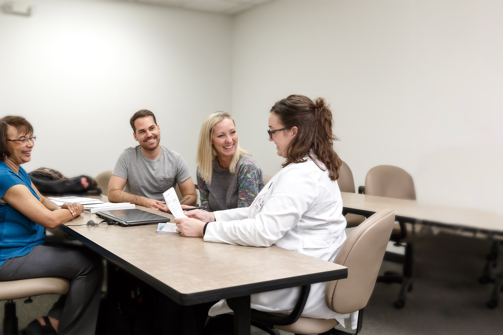 Four people seated at a table. One with a lab coat