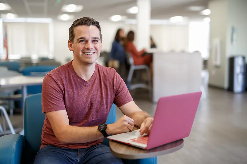 Male student smiling with a laptop