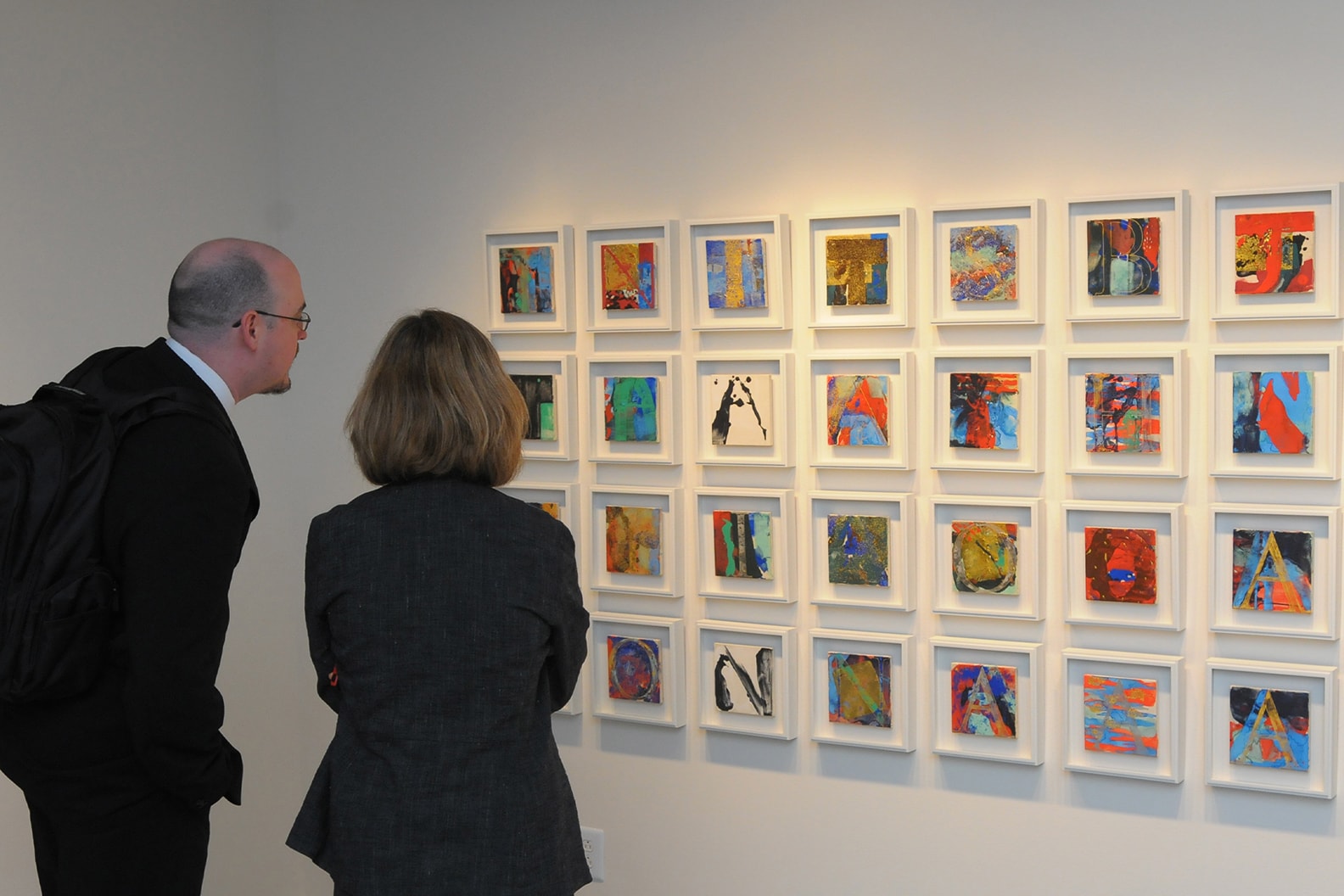 a couple looking at art frames in the wall