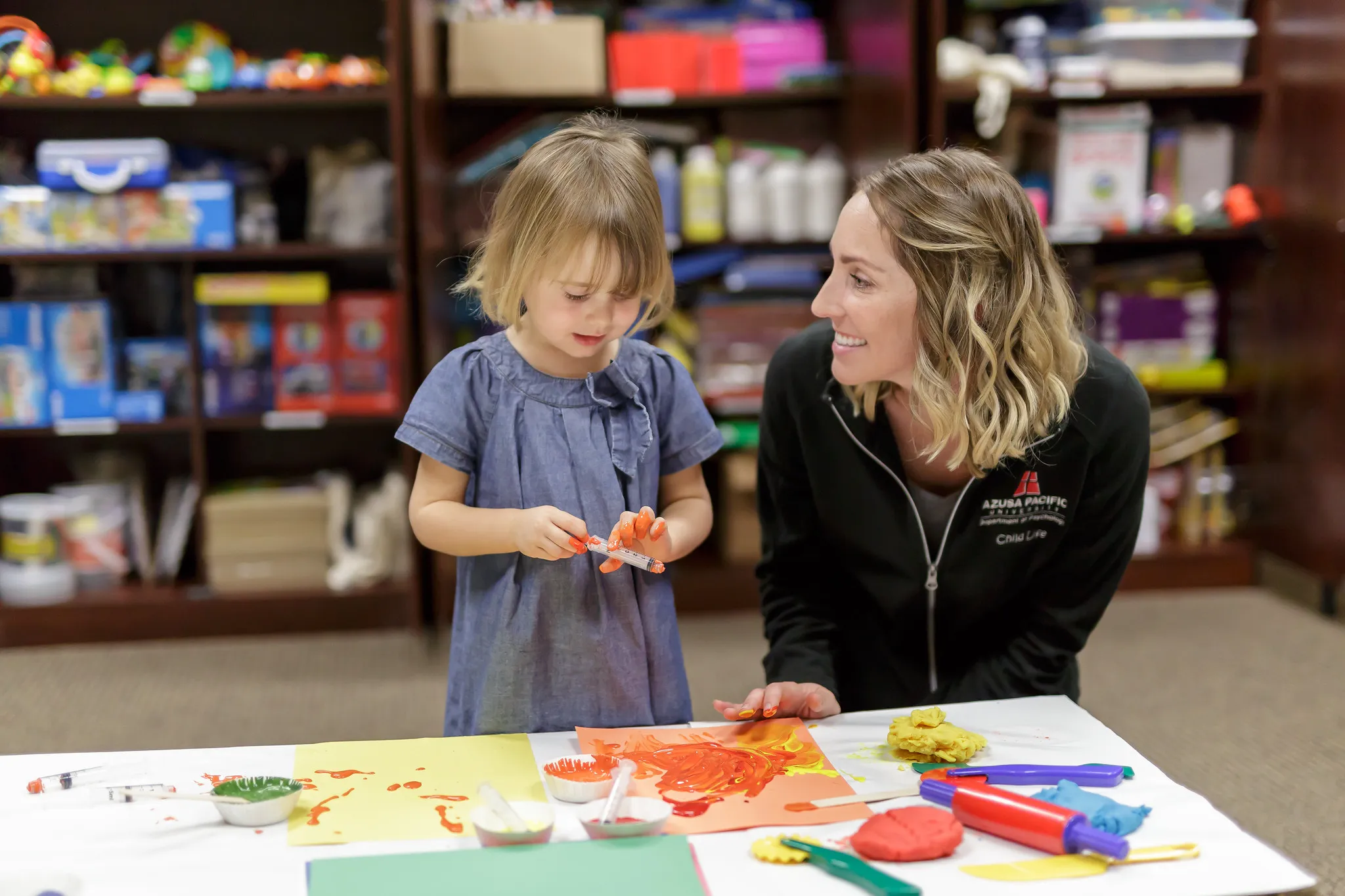 Adult smiling with a child painting
